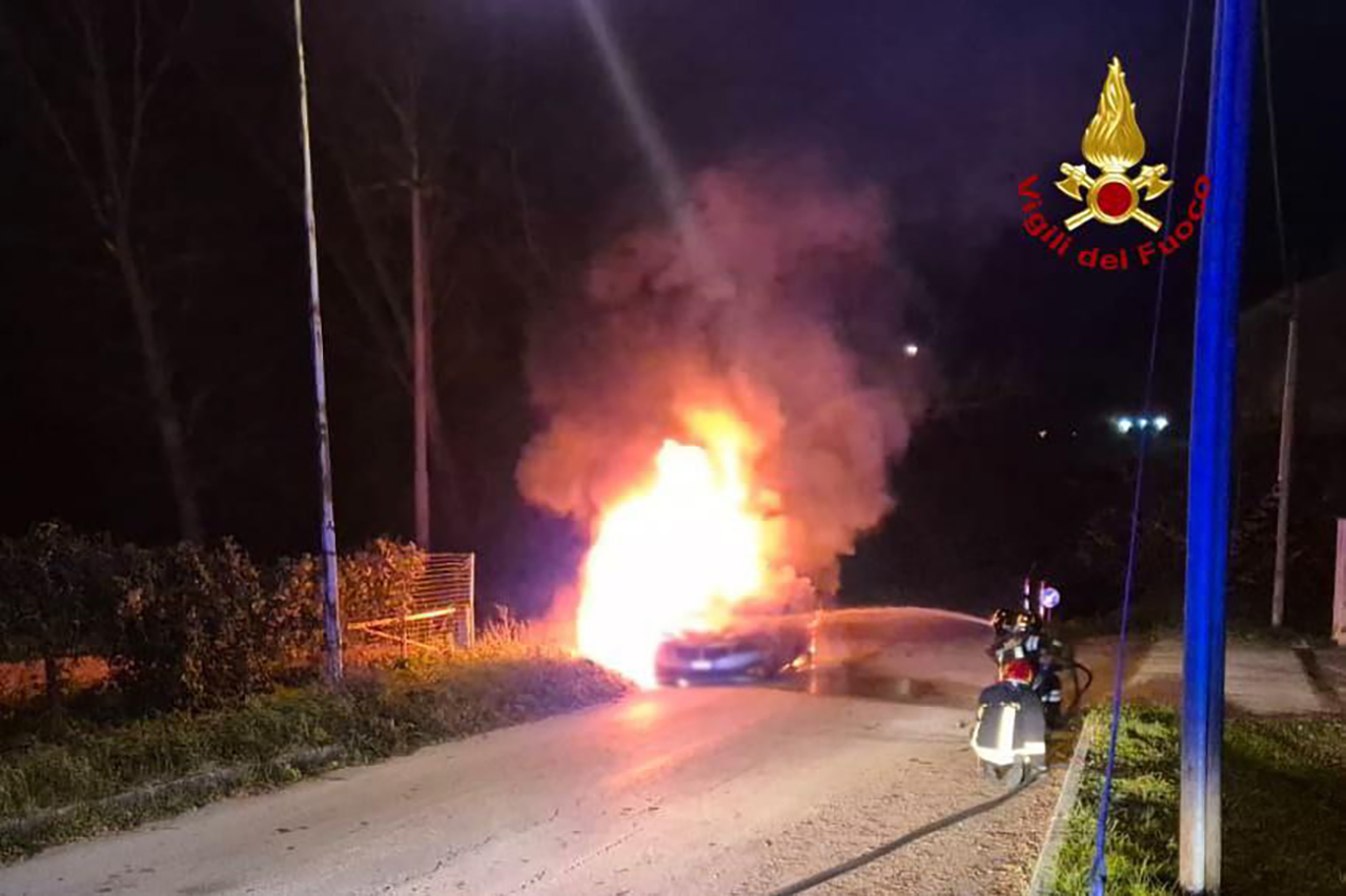 I vigili del fuoco a Camerino mentre cercano di spegnere le fiamme che avvolgono la vettura